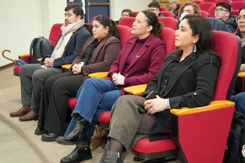 Un grupo de personas sentadas en un auditorio prestando atención.