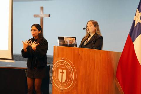 Una mujer presenta un tema mientras otra persona realiza lenguaje de señas en una universidad chilena.