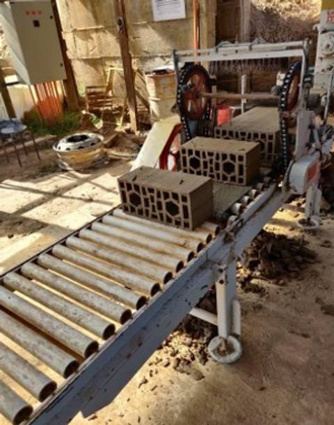 Una máquina industrial que transporta bloques de concreto en una fábrica.