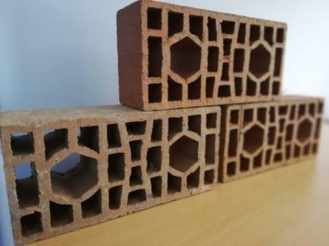 Una pila de ladrillos de arcilla con huecos decorativos apilados sobre una mesa.