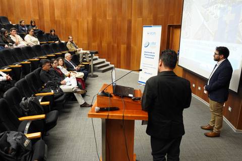 Una presentación en un auditorio con asistentes atentos al expositor.