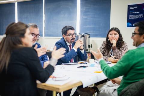 Un grupo de personas se encuentra conversando y colaborando en una mesa de trabajo.