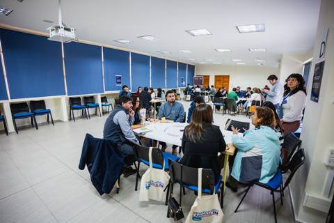 Un grupo de personas participando en una reunión en una sala amplia con mesas.