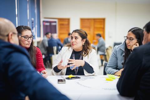 Un grupo de personas conversando y compartiendo ideas en una mesa de trabajo.
