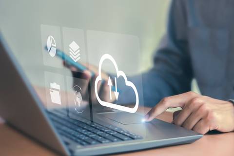 Una persona usando un computador portátil para subir archivos a la nube.