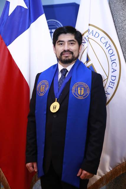 Un hombre con una medalla y una banda en un evento académico en Chile.
