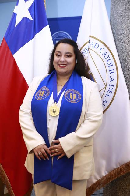 Una persona sonriente con una medalla y banda de prestigio en un evento de graduación.