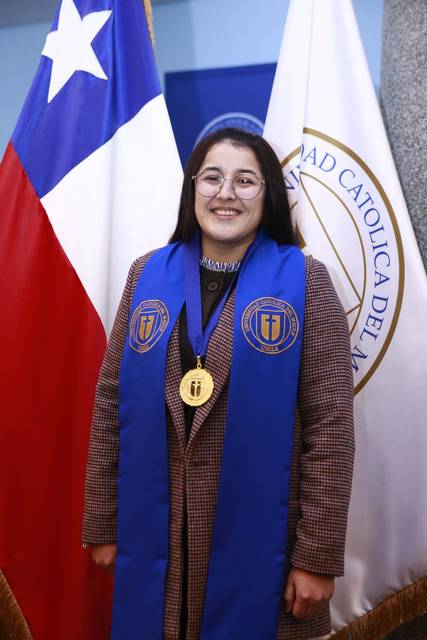 Una estudiante sonriente, vestida con vestimenta formal, se destaca con medalla y estola en un acto académico.