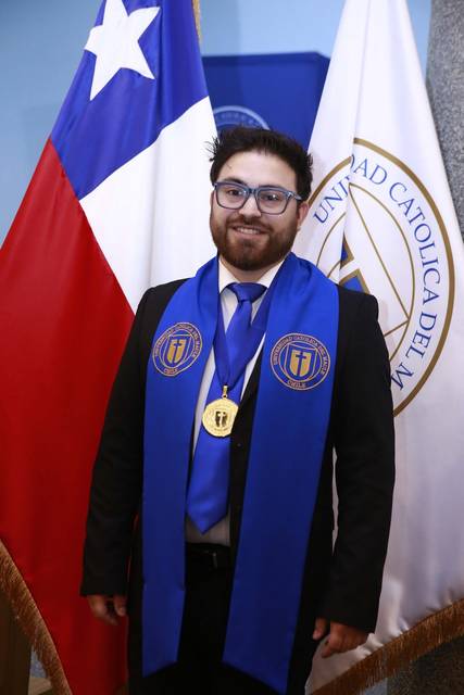 Un graduado de la Universidad Católica del Maule posando con orgullo junto a la bandera chilena.