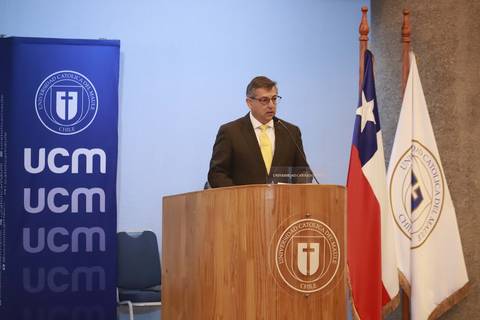Un hombre disertando en una ceremonia en la Universidad Católica del Maule.