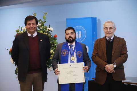 Un grupo de tres hombres posa durante una ceremonia de entrega de títulos académicos.