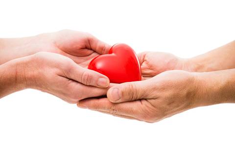 Dos manos que se entregan un corazón rojo, simbolizando amor y conexión.
