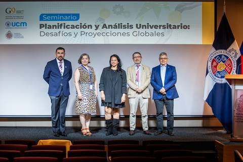 Imagen de un seminario universitario con cinco expositores en el escenario.