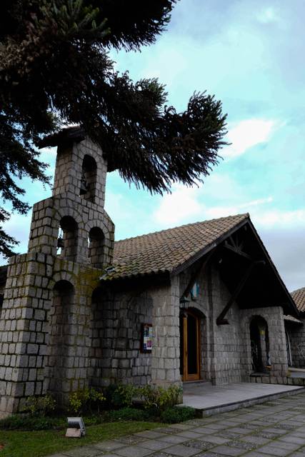 Una casa de piedra con una torre y un cielo nublado en un día tranquilo.