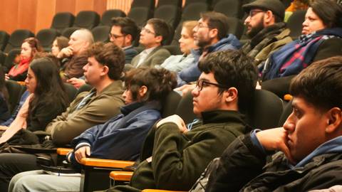 Un grupo de personas escucha atentamente en un auditorio.