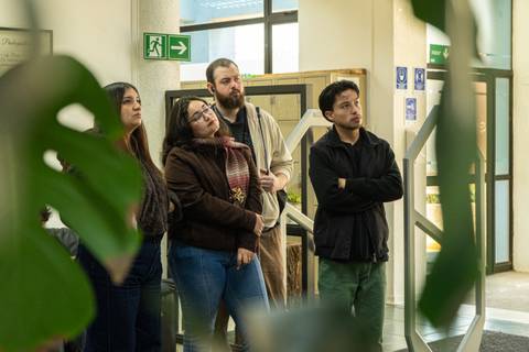 Un grupo de personas observa atentamente algo en un lugar interior.