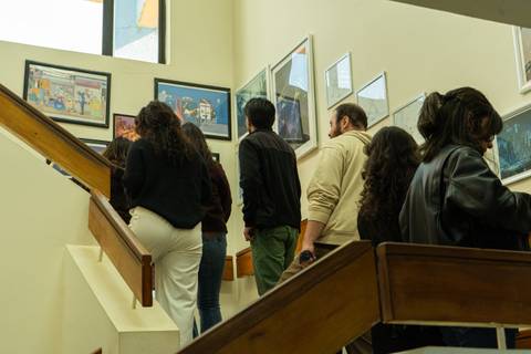 Un grupo de personas subiendo una escalera mientras observan obras de arte en las paredes.
