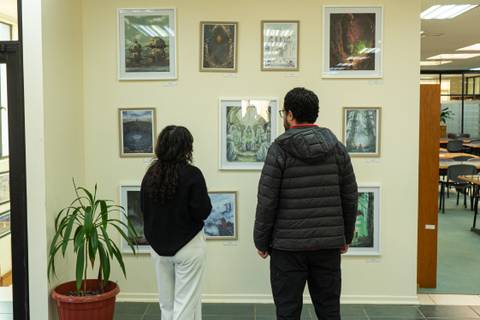 Un par de personas observando obras de arte en una galería.