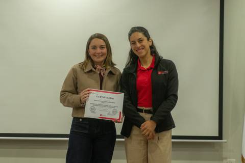 Dos mujeres sonrientes posando con un certificado en un evento.