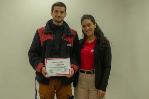 Un par de jóvenes sonrientes posan con un certificado en manos.