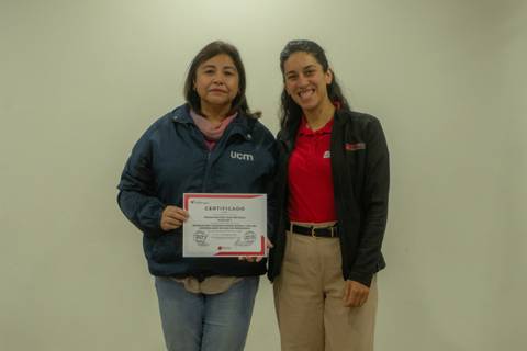 Dos mujeres posan juntas sosteniendo un certificado en un ambiente interior.