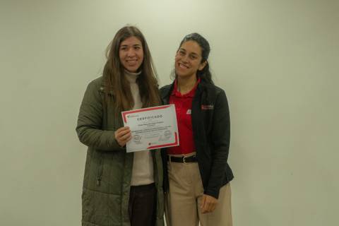 Dos mujeres sonrientes posando con un certificado en mano.