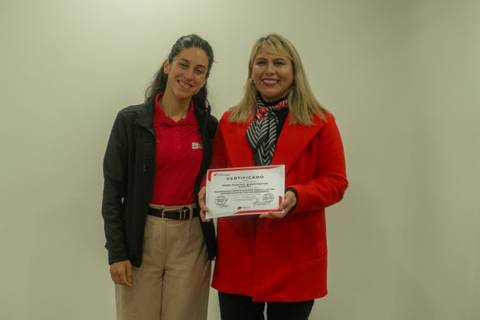 Dos mujeres posando felices con un certificado en la mano.