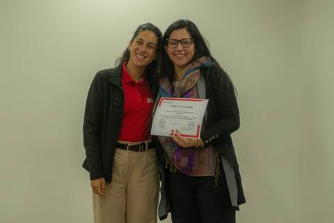 Dos mujeres sonrientes posan juntas con un certificado en mano.