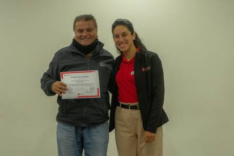 Una persona recibe un certificado de manos de otra en un ambiente amistoso.