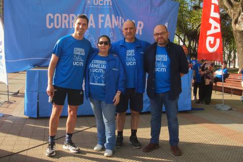 Cuatro personas sonrientes posan en un evento deportivo al aire libre.
