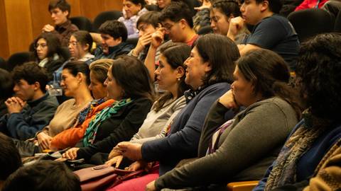 Un grupo de personas sentadas en una conferencia, escuchando atentamente.