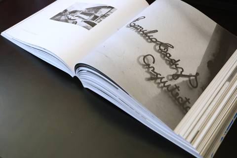 Un libro abierto que muestra una fotografía en blanco y negro de un letrero antiguo.