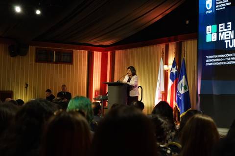 Una mujer está hablando en un podio en un evento oficial en Chile.