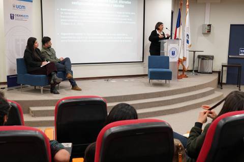Una expositora presenta un tema frente a una audiencia en un evento académico en Chile.