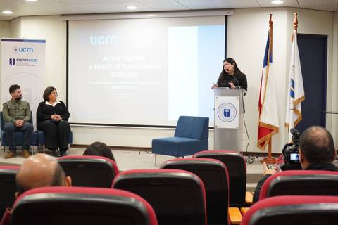 En una charla sobre acceso a la información digital, se observa a una expositora presentando en una sala llena de público.