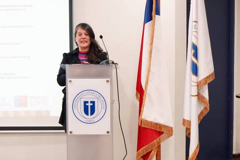 Una mujer está presentando en un evento con banderas chilenas de fondo.