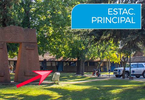 Imagen de un espacio exterior con un arco y edificios al fondo, señalando la entrada principal.