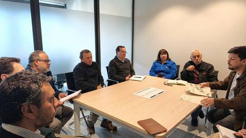 Un grupo de ocho personas discutiendo alrededor de una mesa en una oficina moderna.