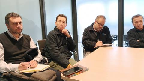 Un grupo de hombres en una reunión, prestando atención mientras uno toma notas.