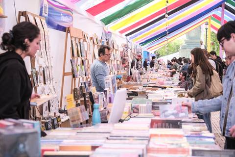 Una feria del libro llena de gente disfrutando de la lectura y comprando textos variados.