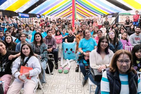 Un grupo de personas sonrientes disfrutando de un evento bajo una colorida carpa.