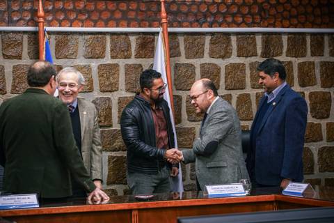 Un grupo de personas se saluda y conversa en una reunión oficial en un ambiente de trabajo.