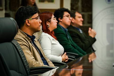 Un grupo de personas sentadas en una reunión, prestando atención a lo que sucede frente a ellos.