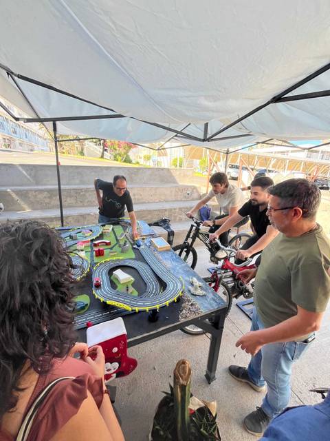 Un grupo de amigos se divierte jugando con un circuito de autos en un espacio al aire libre.