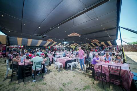 Un ambiente festivo lleno de gente disfrutando en un gran comedor al aire libre.
