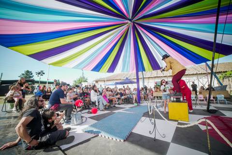 Un show de circo al aire libre con un gran toldo de colores y un público entusiasta.