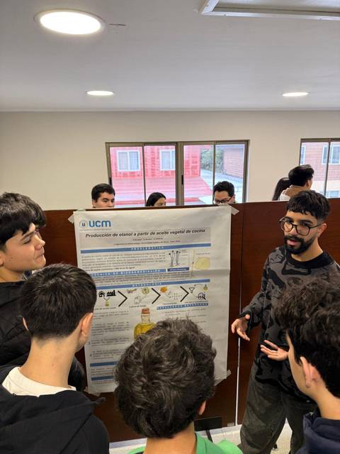 Un grupo de estudiantes observa un póster sobre la producción de etanol a partir de residuos vegetales en una exposición.