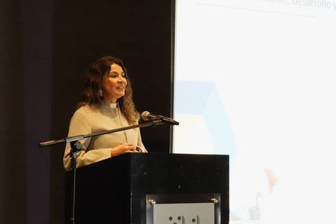 Una mujer habla en un escenario durante una presentación.