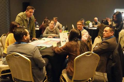 Un grupo de personas conversando y colaborando en una mesa durante un evento en Chile.
