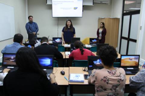 Un grupo de personas está asistiendo a una presentación en un aula con computadoras portátiles.